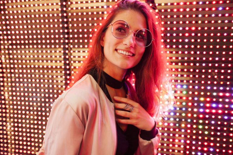 mujer sonriendo delante de panel led de color rojo